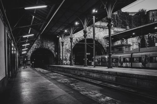 Free Black and white photograph of a vintage train station at night with a train and tunnels. Stock Photo