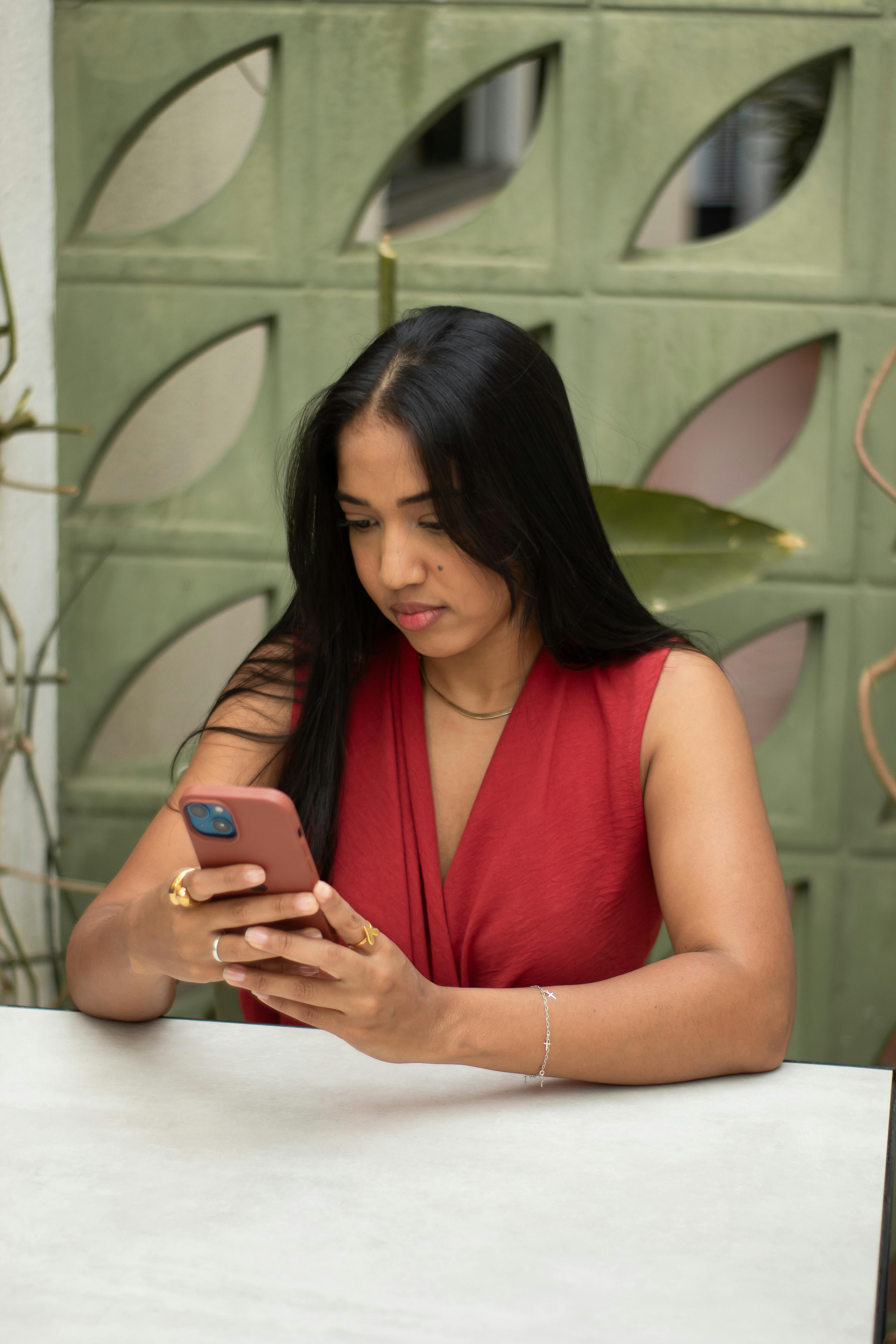 Woman in a red dress engaging with a smartphone, indoors. Modern lifestyle and communication.