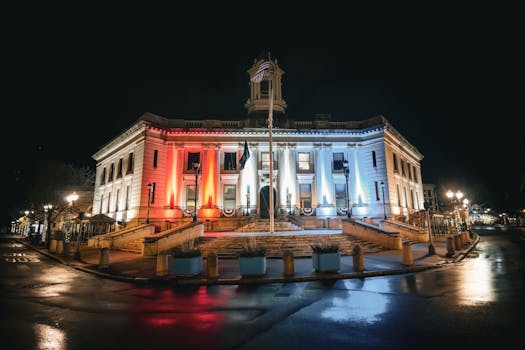 A beautifully lit historic courthouse building with red, white, and blue lights reflecting patriotism.