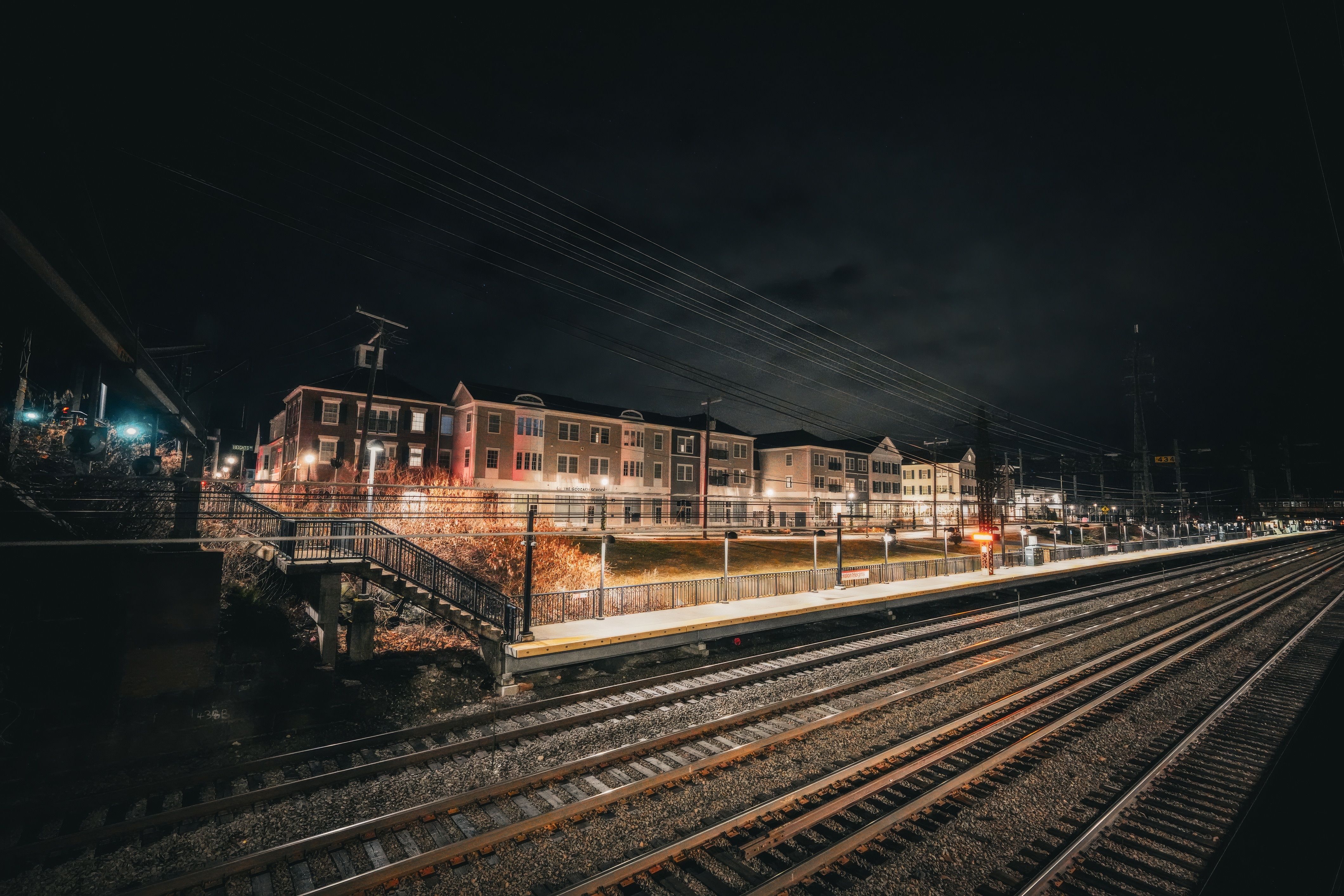 Long-exposure shot of a train station at night, showcasing urban architecture and railroad tracks.