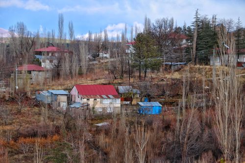 Free A picturesque rural village surrounded by autumn trees and hills. Stock Photo