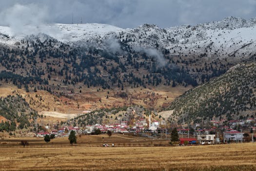 Explore the serene landscape with snow-capped mountains overlooking a quaint village.