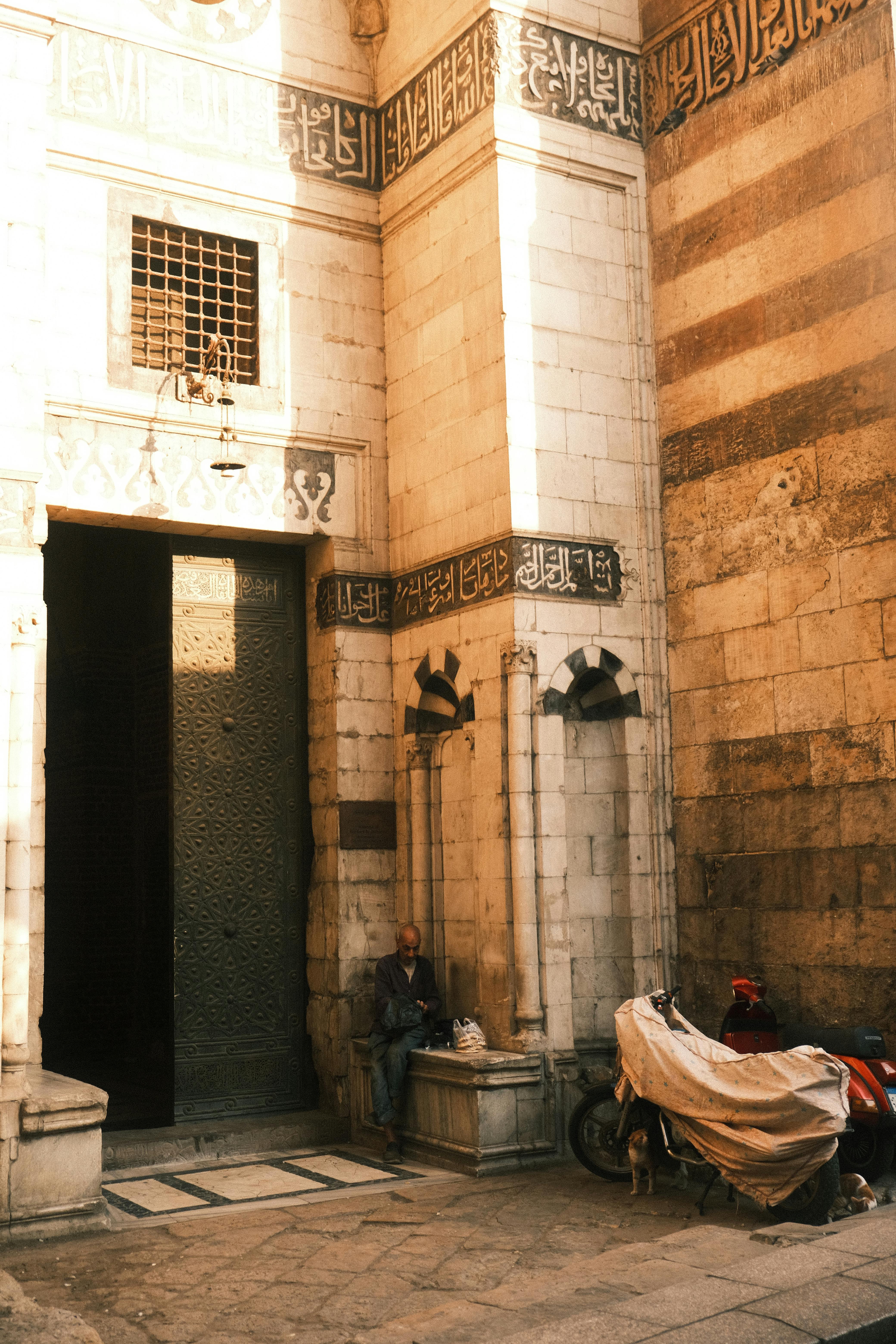 A historic street scene in Cairo featuring ancient architecture and a resting figure.