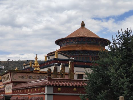 A traditional Tibetan Buddhist monastery with vibrant colors and ornate architecture set against a cloudy sky.