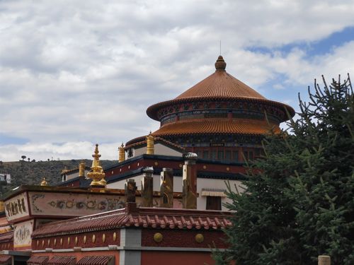 Free A traditional Tibetan Buddhist monastery with vibrant colors and ornate architecture set against a cloudy sky. Stock Photo