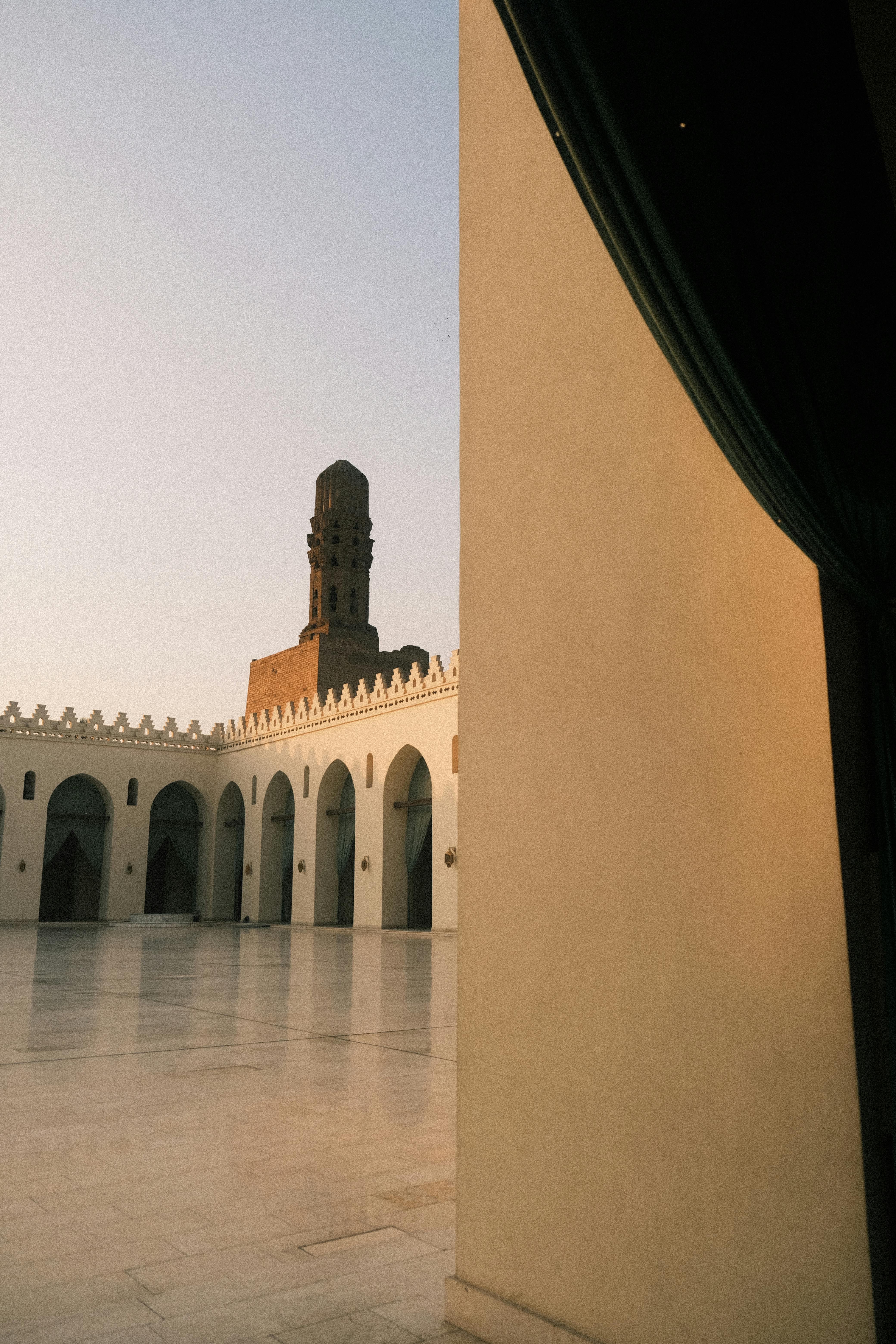 Beautiful courtyard of a historic mosque with a minaret, captured at sunset.