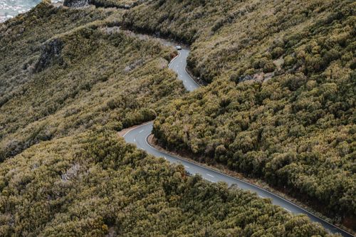 Free Aerial view of a curvy road through lush green hills in Madeira. Serene and picturesque. Stock Photo