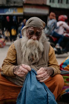An elderly man with vitiligo sewing in a busy street of Varanasi, India.