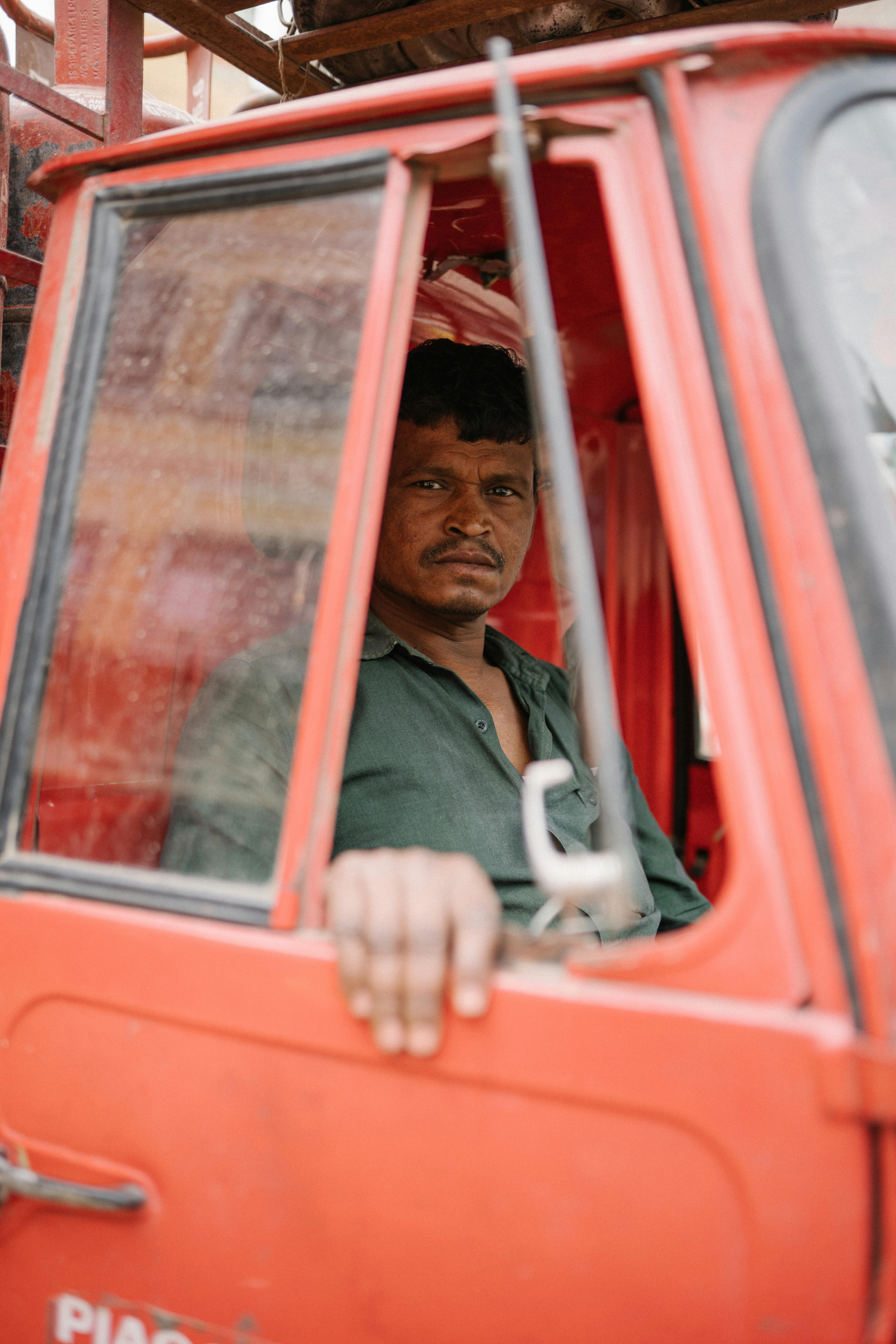 Man sitting in a red vehicle in Varanasi, Uttar Pradesh, conveying local culture.