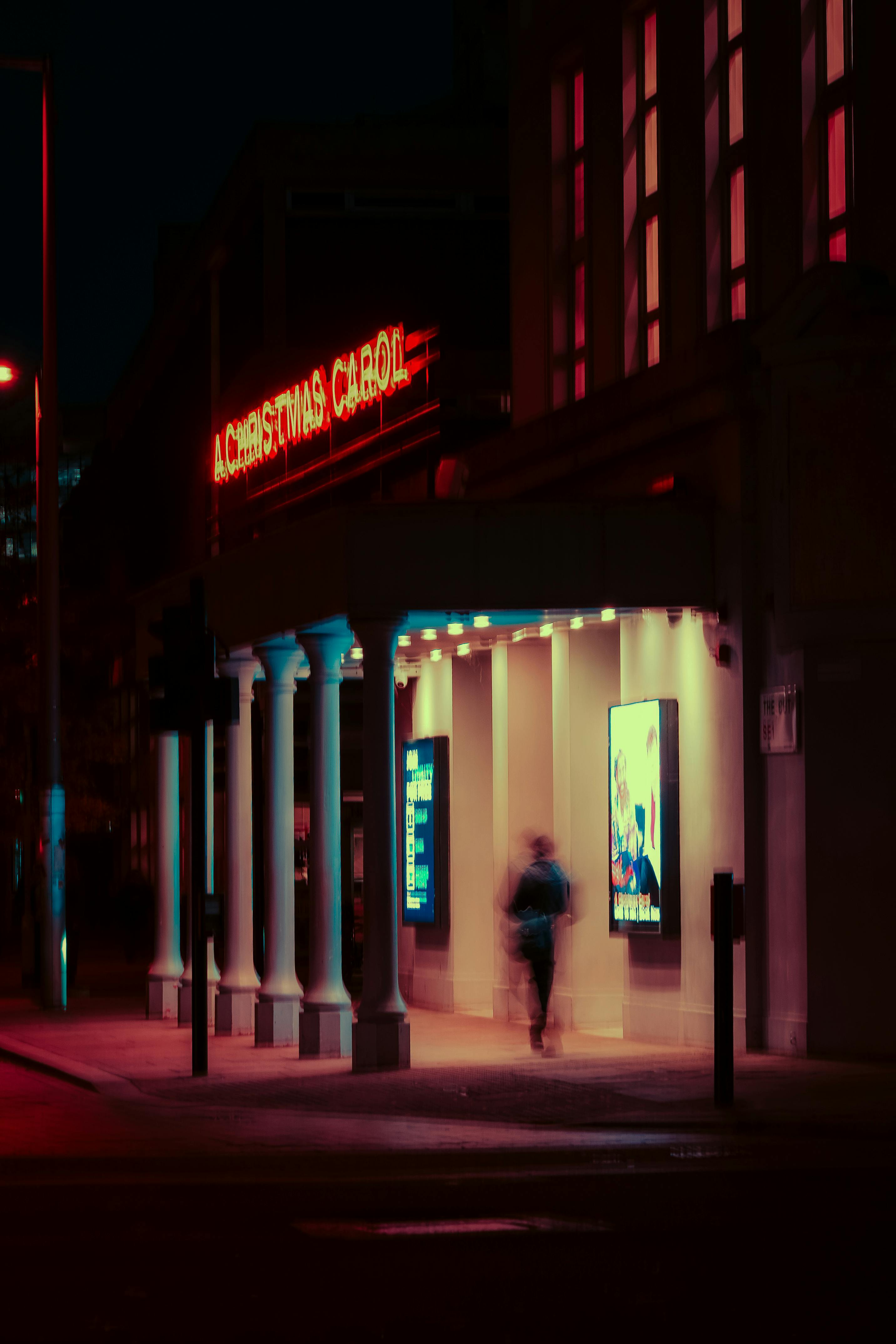 bezplatná Filmový noční pohled na vchod do divadla v Londýně s neonovými světly a rozmazáním pohybem. Základová fotografie