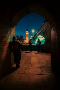 Atmospheric night view of Big Ben through an urban archway in London, England.
