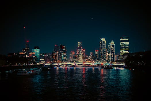 A vibrant night view of the London skyline featuring neon lights reflecting on the Thames River.