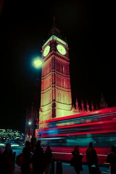 Vibrant long exposure of Big Ben with a motion blur red bus showcasing London's nightlife.