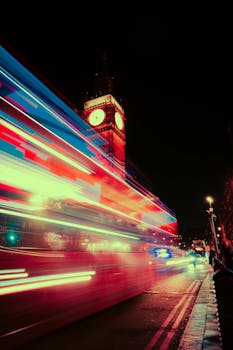 Dynamic nighttime image capturing Big Ben with colorful neon light trails in London.