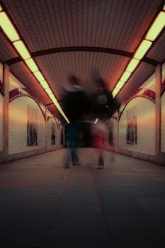 Ethereal movement in dimly lit London underground tunnel, captured with long exposure.