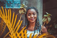 一位头发编成辫子的女人微笑着，她的肖像被植物环绕