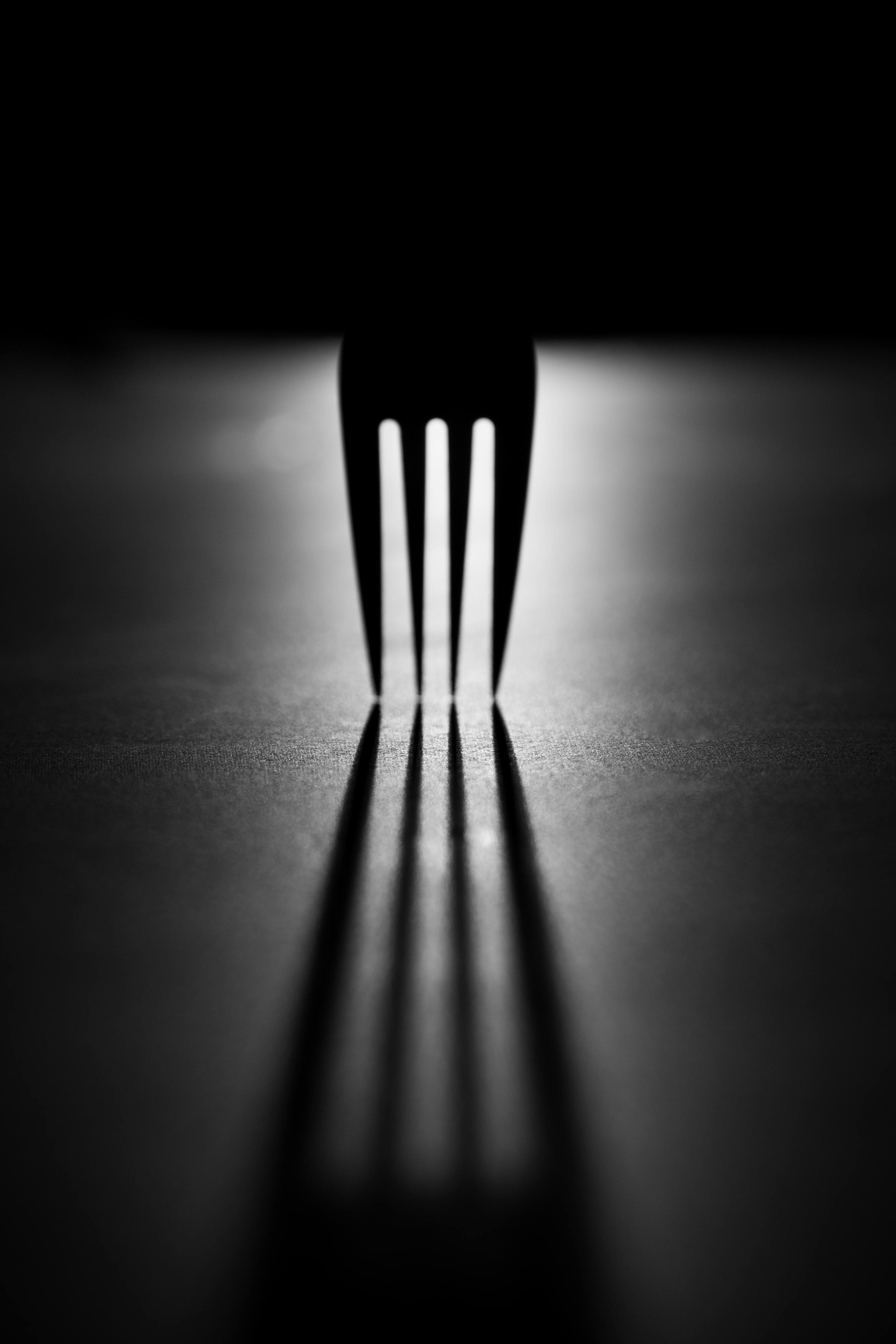 Kostenlos Künstlerische Schwarz-Weiß-Fotografie einer Gabel, die dramatische Schatten wirft. Stock-Foto