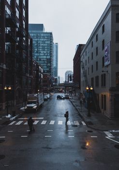 Moody city street view with buildings and pedestrians at dusk.