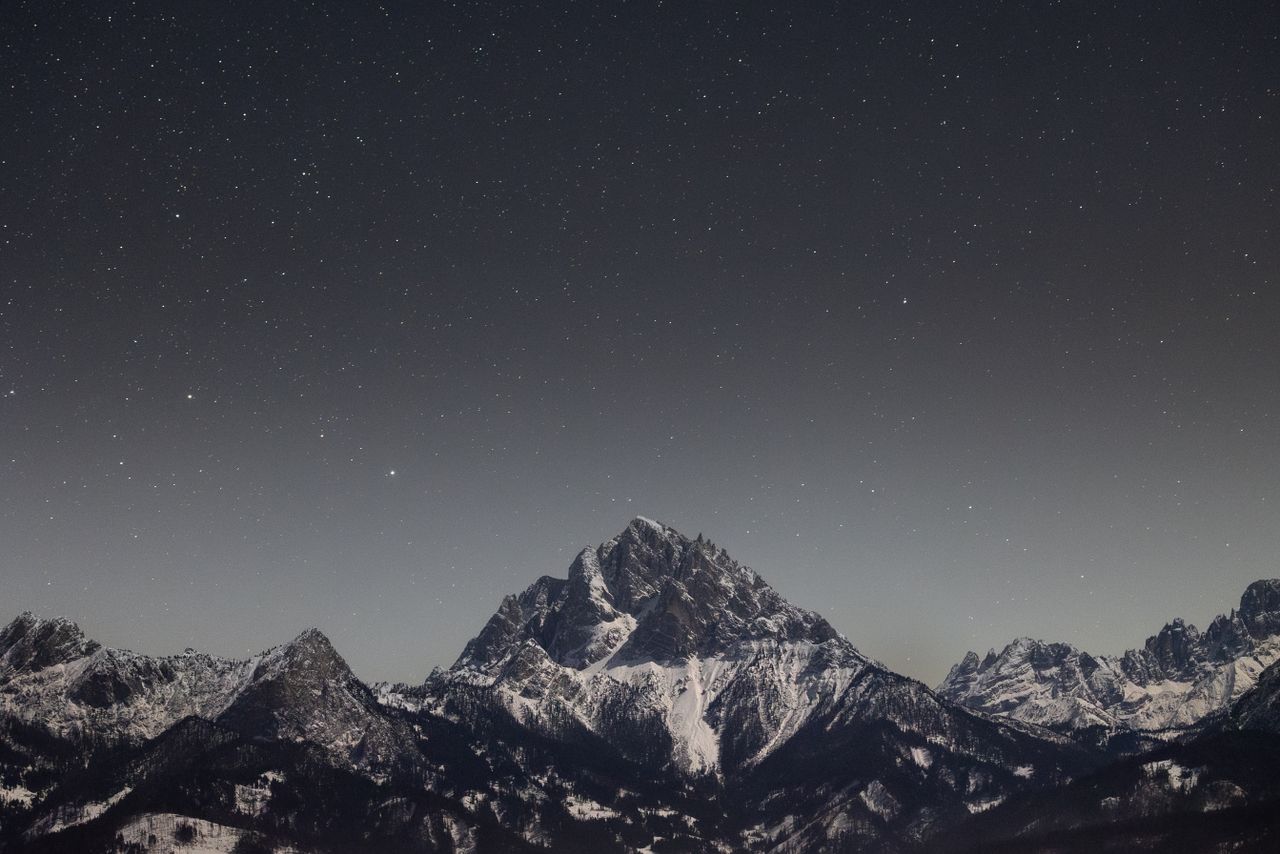 stunning view of a starry night sky above snow capped mountains captur