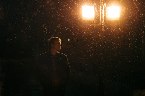Man in Black Jacket Standing Near A Lamp Post