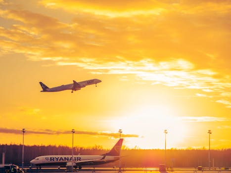 Airplanes departing and grounded at Wrocław Airport during a vibrant sunset.
