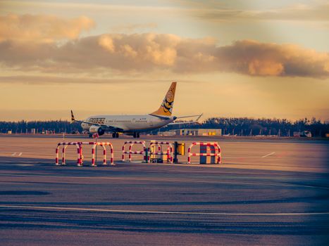 Airplane preparing for takeoff at sunset at Wrocław Airport in Poland.