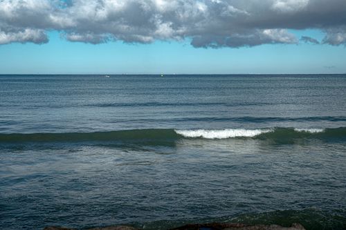 Free Gentle ocean waves under a cloudy sky create a serene seascape, perfect for relaxation and tranquility. Stock Photo