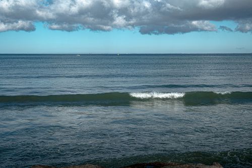 Free A serene ocean scene with gentle waves and a cloudy sky on a calm day. Stock Photo