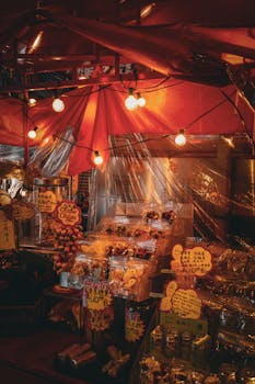 Colorful night market stall in Hong Kong illuminated by glowing lights, showcasing local street food and snacks.