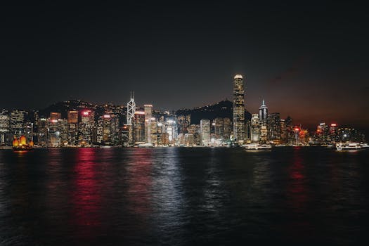 Experience the vibrant Hong Kong skyline at night with illuminated skyscrapers reflecting on Victoria Harbour.