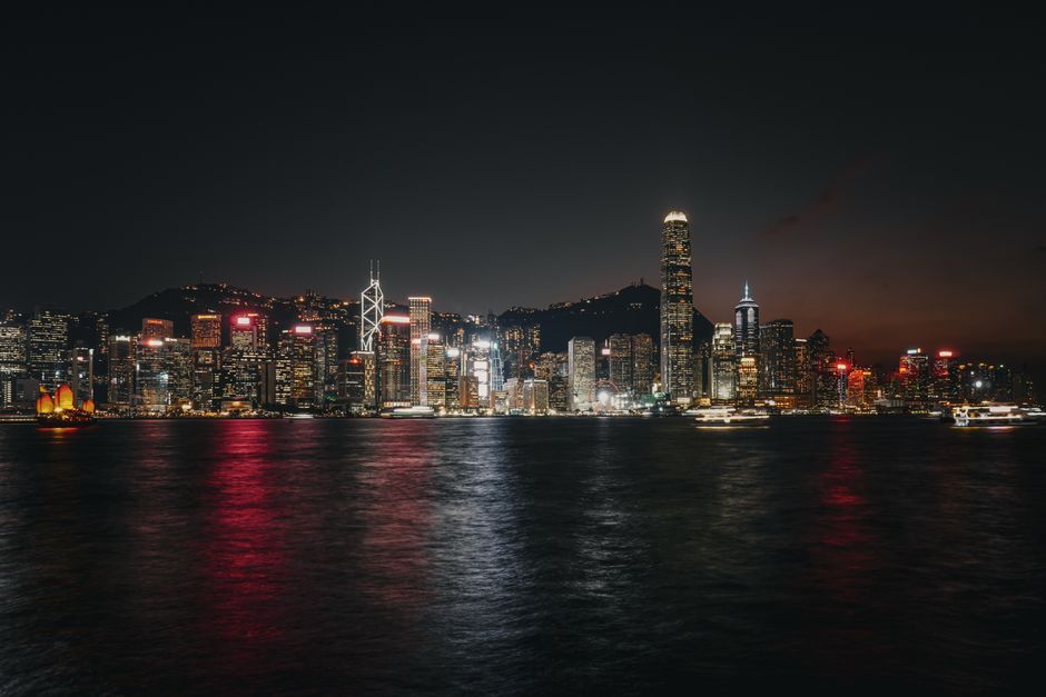 Experience the vibrant Hong Kong skyline at night with illuminated skyscrapers reflecting on Victoria Harbour.