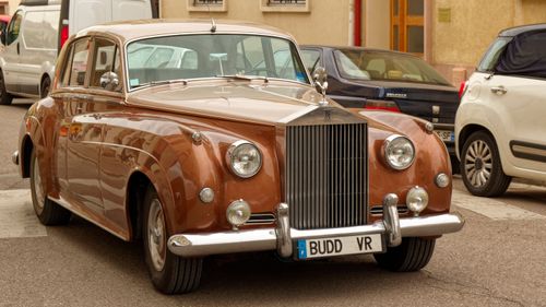 Free Classic brown Rolls Royce parked on a city street with vintage charm and elegance. Stock Photo