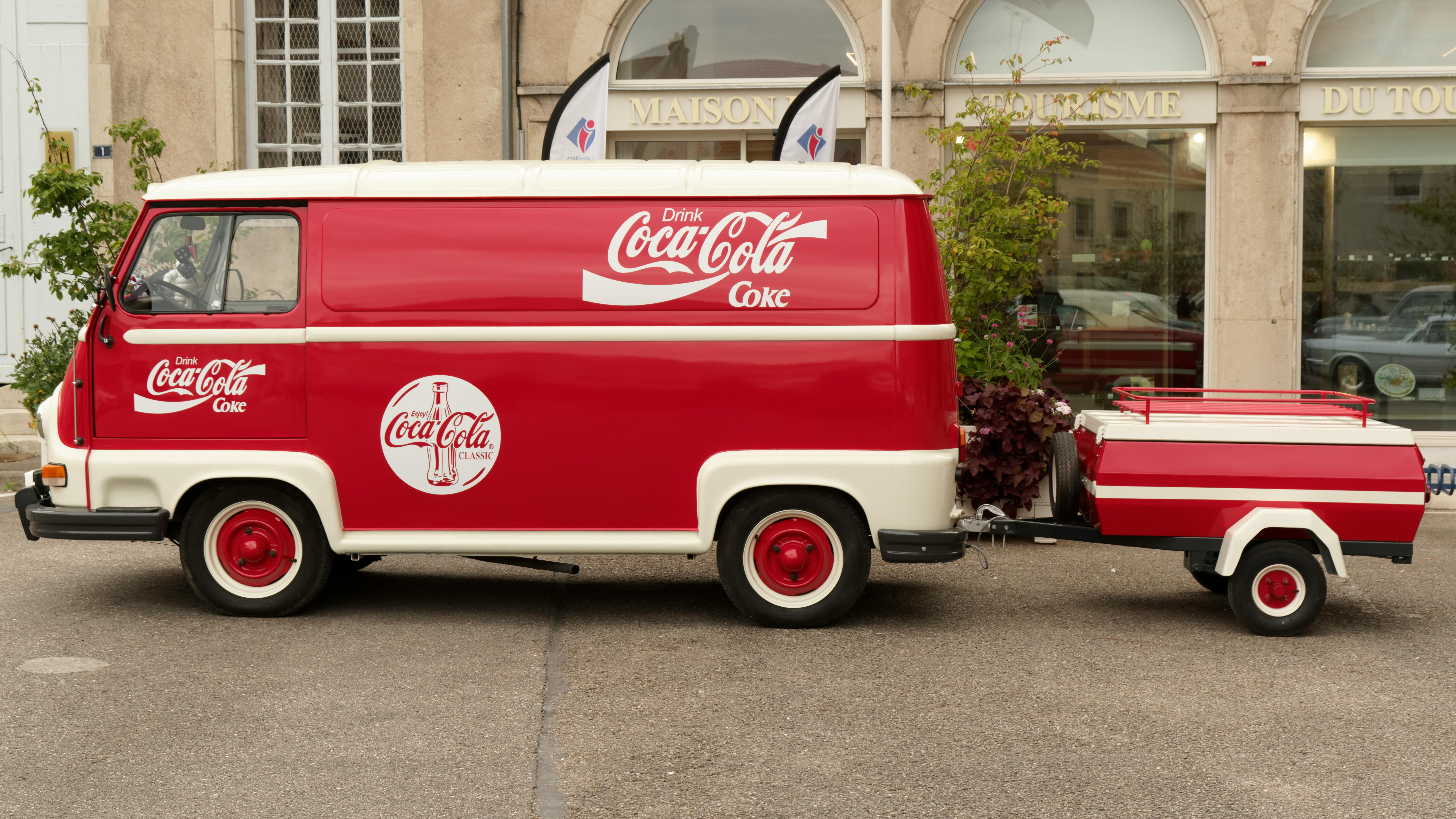 Classic red and white Coca-Cola van with matching trailer parked outdoors for promotional display.