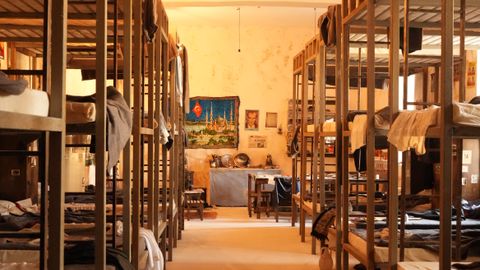 Warmly lit dorm room with wooden bunk beds and cozy atmosphere.