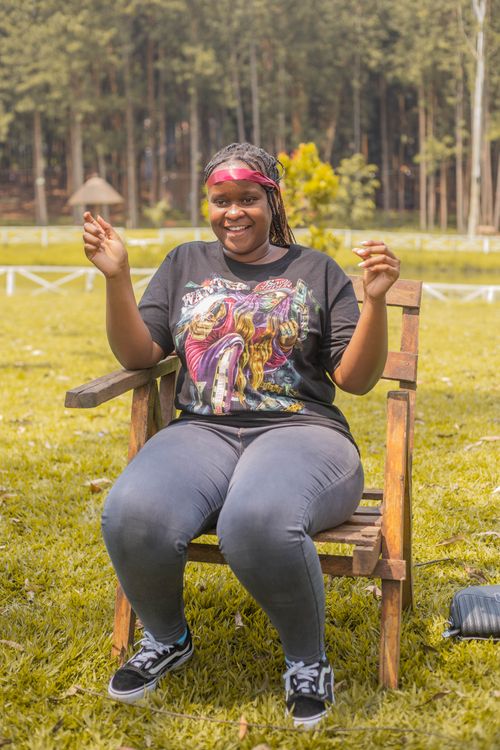 Free Smiling woman enjoying a sunny day sitting in a park with a forest backdrop. Stock Photo