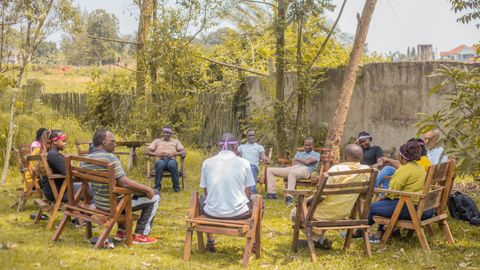 A group of adults having a team meeting outdoors in a garden during the day.