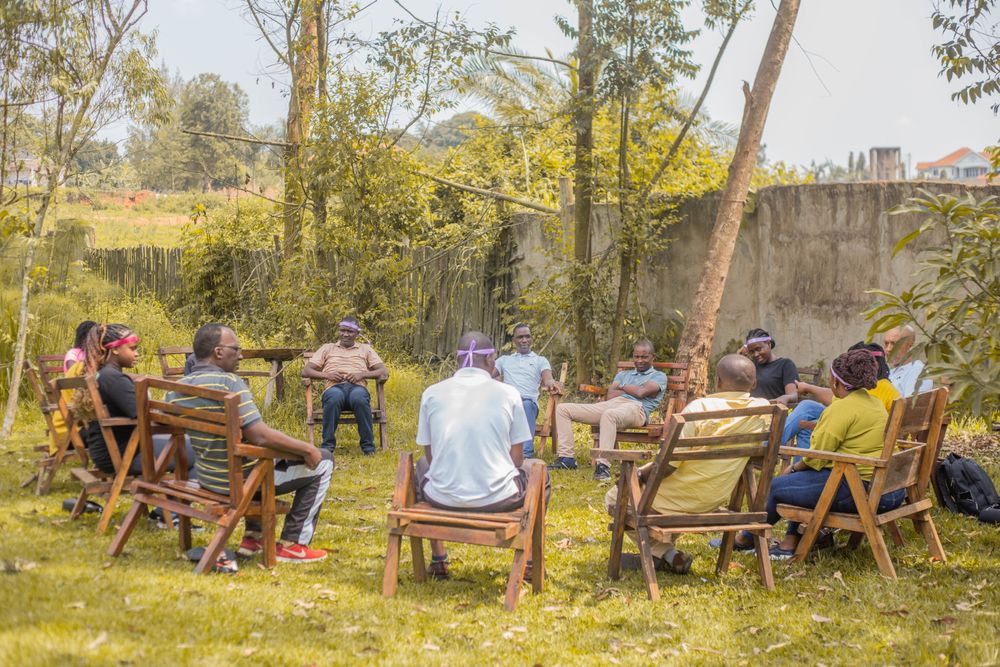 A group meeting outdoors in a garden setting, seated in a circle.