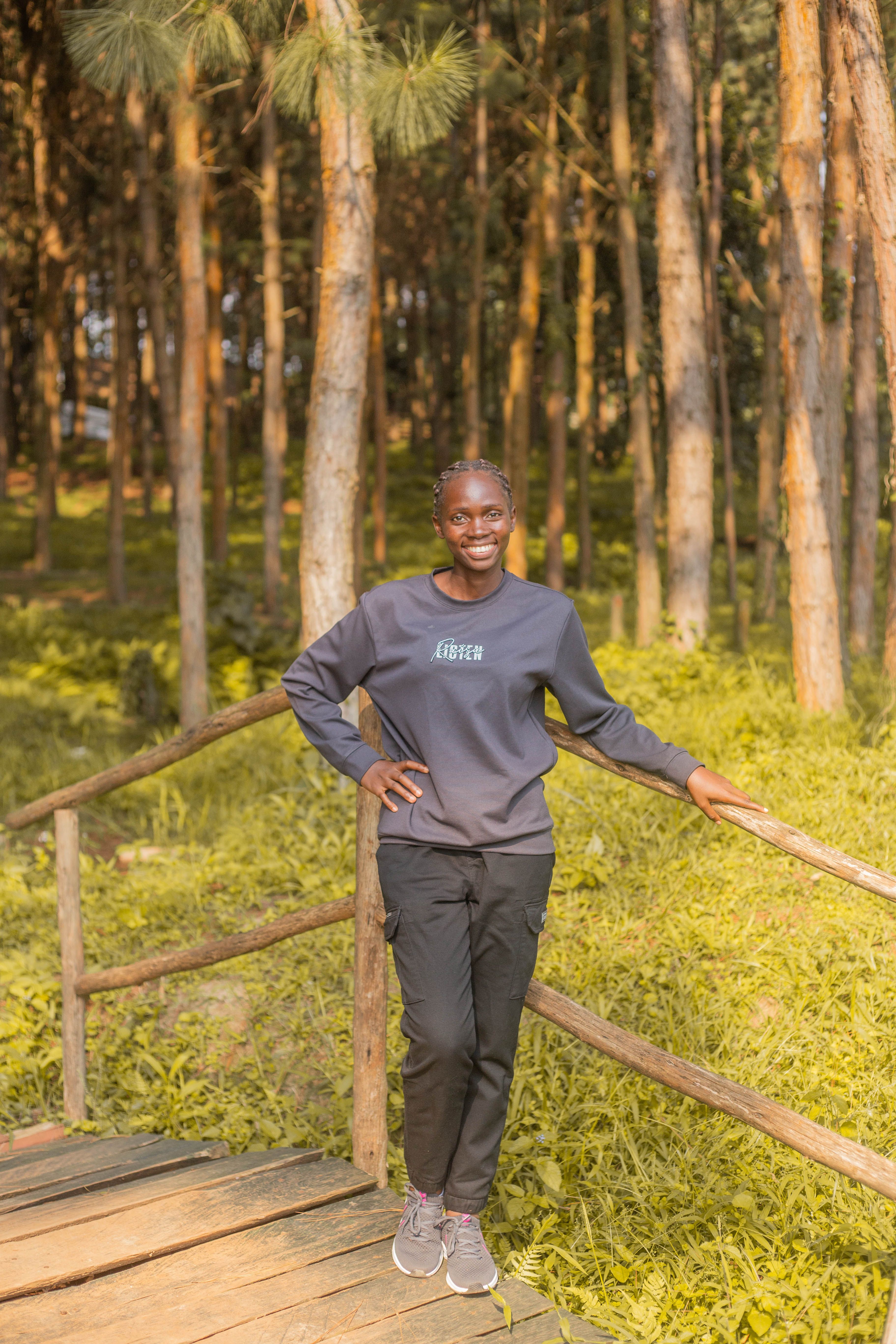Smiling woman in a sunlit forest, enjoying nature on a wooden path.