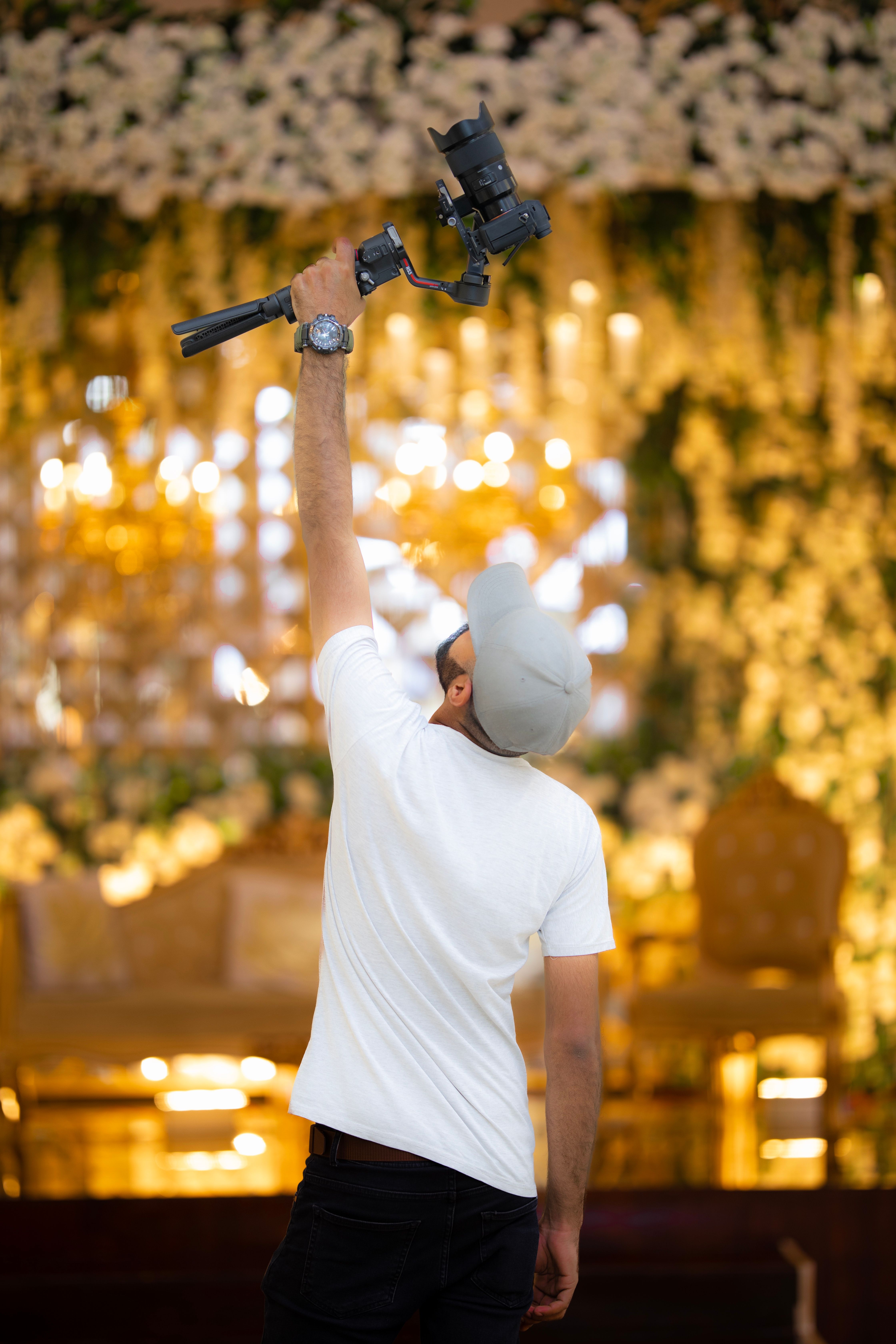 Photographer raises camera inside a beautifully decorated event venue.