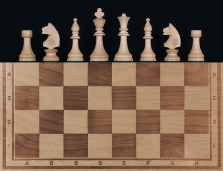 Seven wooden chess pieces arranged on a wooden chessboard with a black background.