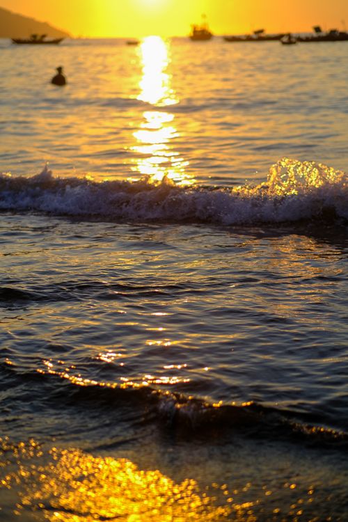 Free A tranquil sunrise over Da Nang beach with golden reflections and gentle waves. Stock Photo