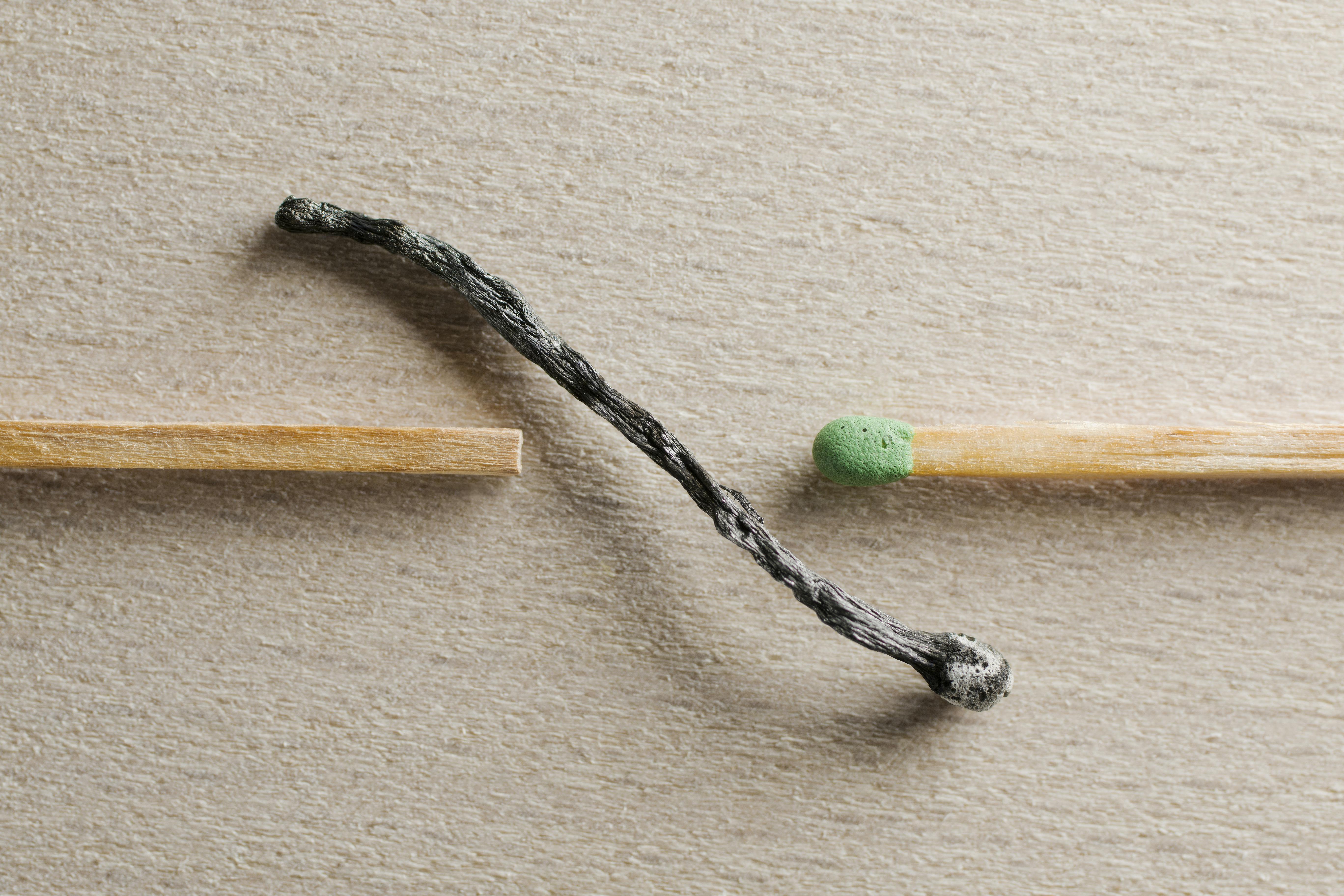 Artistic depiction of contrast between a burnt and unused match on a textured surface.