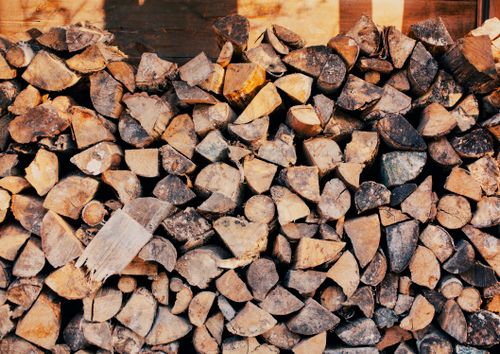 Free Pile of chopped firewood neatly stacked outdoors in warm sunlight. Stock Photo