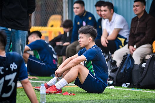 Youth soccer players take a break on an artificial turf field in Hanoi, Vietnam, reflecting on the game.