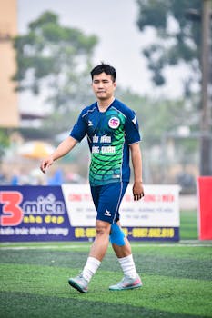 East Asian male soccer player walking on artificial turf in Vietnam.