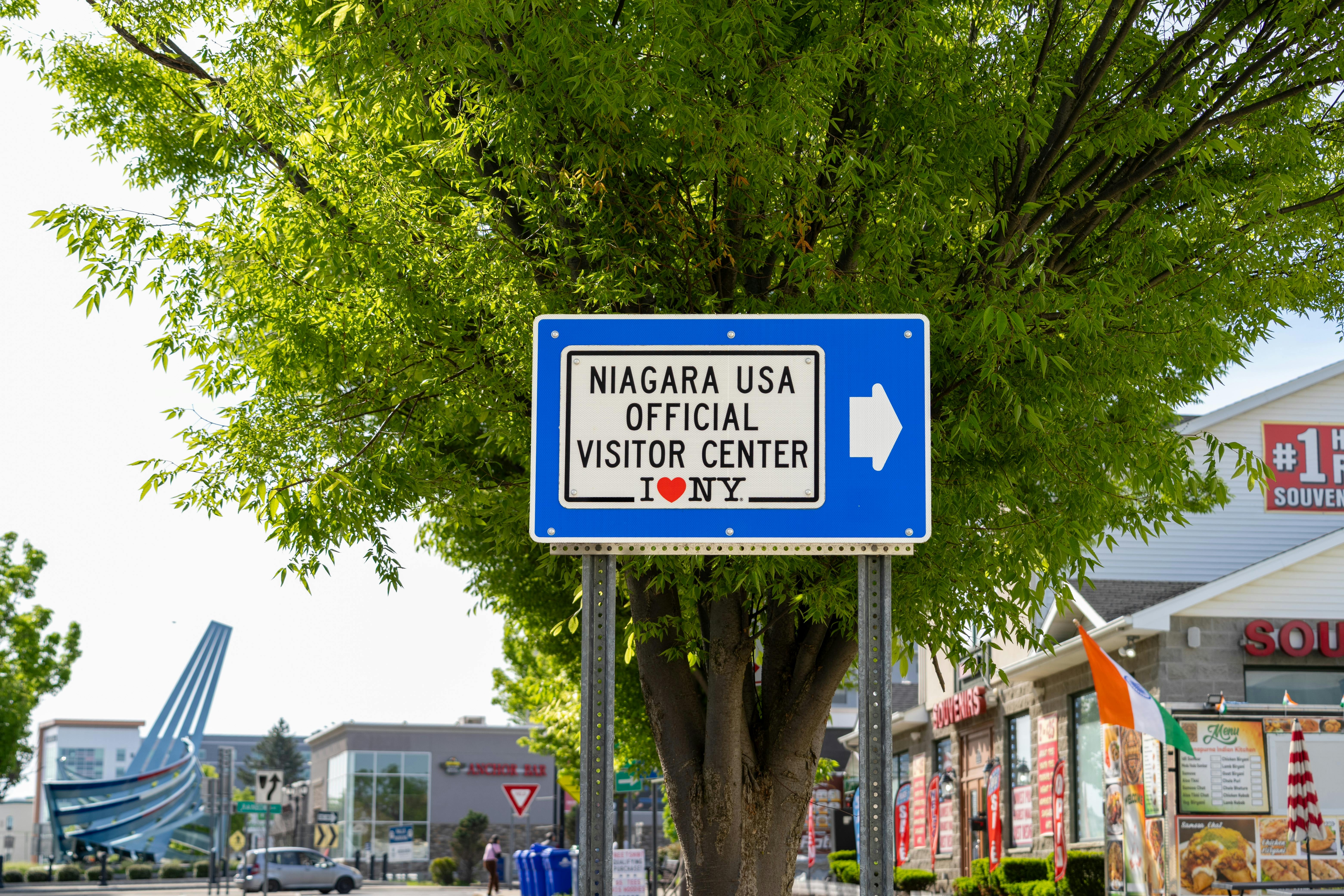 A sign directing visitors to the Niagara USA Official Visitor Center on a sunny day.