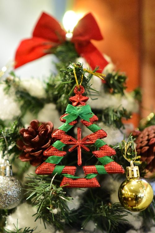 Free Close-up of a Christmas tree adorned with ornaments, pinecones, and a red bow, creating a festive holiday ambiance. Stock Photo