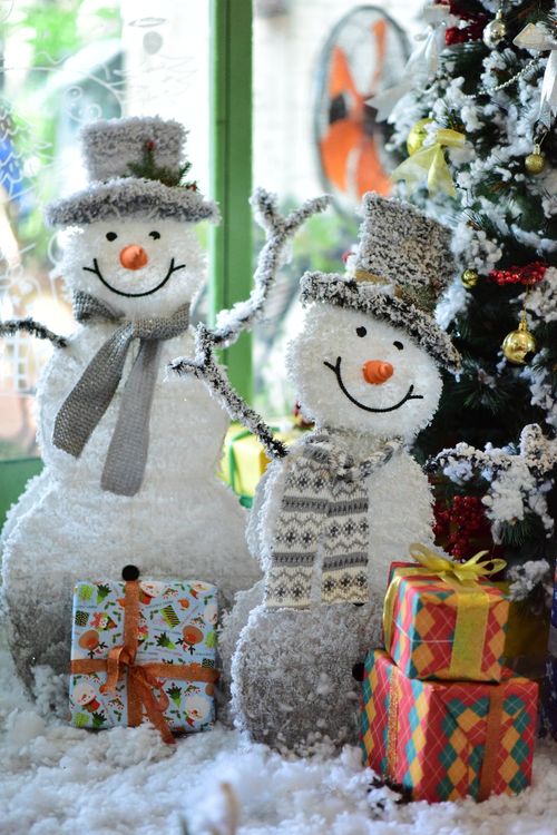 Free Cheerful snowmen with Christmas gifts and tree, creating a festive winter scene. Stock Photo