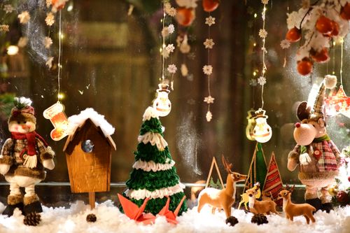 Free A charming Christmas window display featuring reindeer, snowmen, and holiday lights. Stock Photo