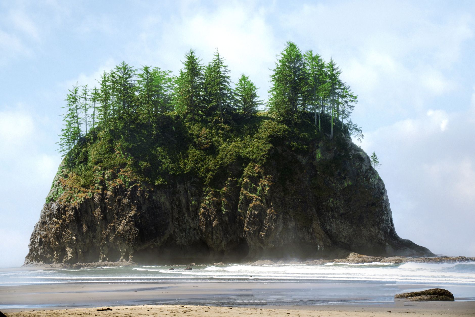 Lush green sea stack surrounded by ocean waves on a sunny day in Washington.